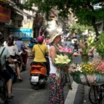 A lively urban street scene with a florist selling colorful flowers from a bicycle cart.